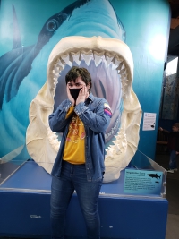 Yuri looking mock-frightened in front of the model of megalodon shark teeth