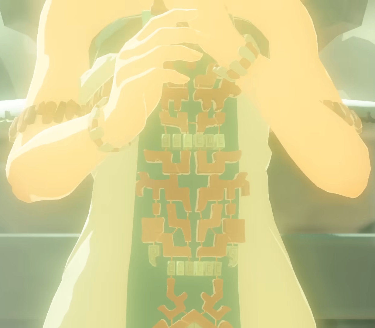 A feminine figure in white, face hidden, with a build like Breath of the Wild Zelda's. She is either holding something green, decorated with gold and stone, or has a green stripe of intricately decorated fabric down the front of her dress